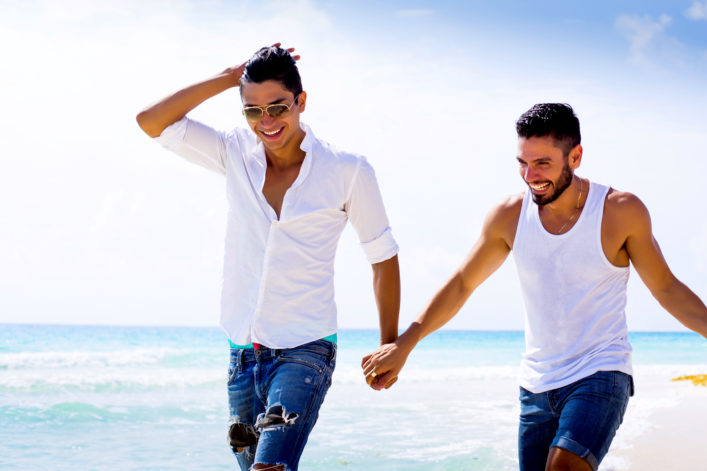 Twee mannen houden handen vast tijdens een strandwandeling